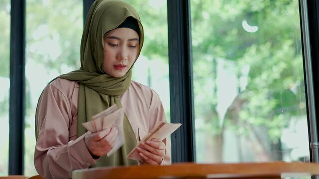 Young muslim woman split money and laid aside for expenses.