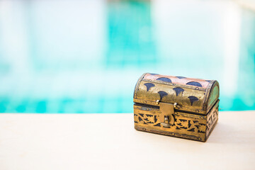Vintage style wooden treasure box with space on blurred blue water background, selective focus, hidden treasure