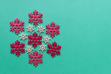 Christmas greeting card with red white wooden snowflakes on green background. Photo with copy blank space.