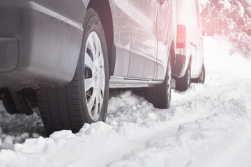 Cars parked standing in messy winter snow. Difficult driving weather conditions.