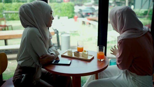 Pretty muslim woman and friend selfie in coffee shop