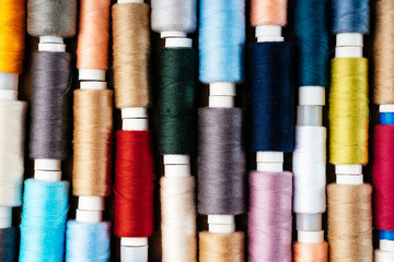 Many different reels with threads, flat lay, top view. Colored threads, close-up, bright background. Cutting and sewing clothes concept. Accessories for needlework