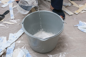 Mixing white plaster in a bucket with a stirrer. Close-up.