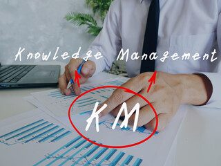 Conceptual photo about KM Knowledge Management with written text. Man signing document on...
