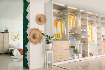 Big wardrobe with different clothes and accessories in studio apartment