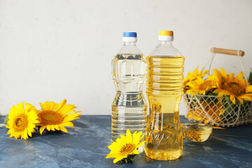 Plastic bottles of sunflower oil on color background