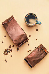 Foil bags and cup of hot coffee on light background