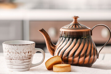 Stylish teapot, cookies and cup on light table in room