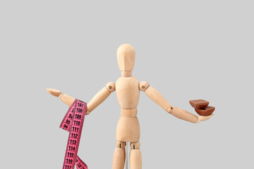 Wooden mannequin with measuring tape and chocolate on light background