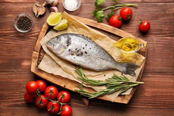 Raw dorado fish with ingredients on wooden background
