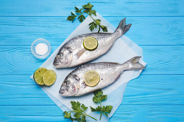 Raw dorado fish with parsley and lime on color wooden background