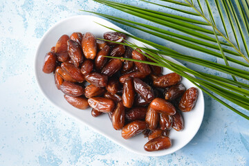 Plate with sweet dates on color background