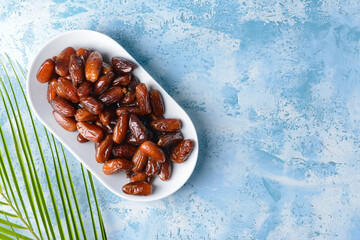 Plate with sweet dates on color background