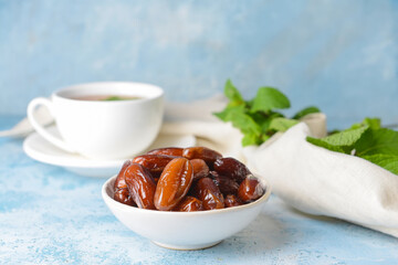 Bowl with sweet dates and cup of tea on table