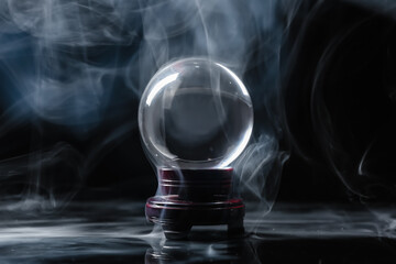 Crystal ball of fortune teller in smoke on dark background