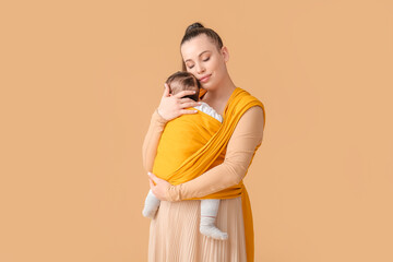 Young mother with little baby in sling on light background