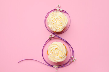 Figure 8 made of violet ribbon and cupcakes on color background. International Women's Day celebration