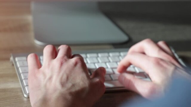 &Eacute;tudiant (homme) tapant sur un clavier d'ordinateur fixe, vue rapproch&eacute;e par dessus l'&eacute;paule