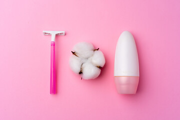 Pink disposable razor and cotton flower on pink background