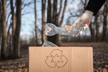 Plastic bottle, garbage are collected in a box for waste processing in the yard.Volunteer, a man in gloves collects garbage.