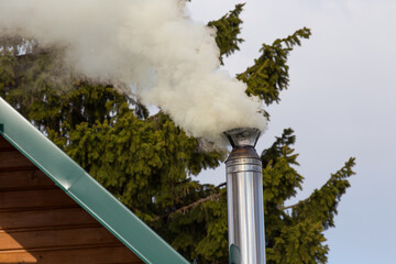 Smoke comes from the chimney. Stove heating. Pollution of the atmosphere by soot.