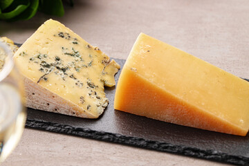 Several different pieces of cheese served on black stone flat plate