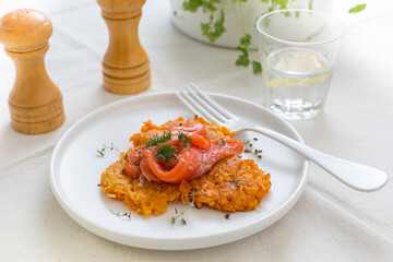 Sweet potato pancakes with red fish and herbs on the table, place for text or recipe