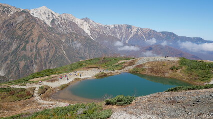 beautiful mountain view, floating clouds and emerald green pond at Hakuba, Japan, early autumn