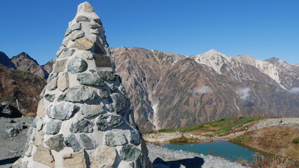 stone monument, mountain view and green pond at Hakuba, Japan, early autumn