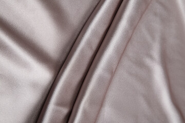 Colored silver textile satin fabric folded in folds and waves with highlights and texture