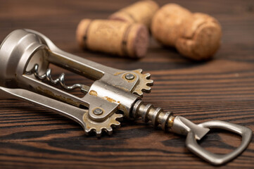 Corkscrew and corks from wine bottles on a wooden table.