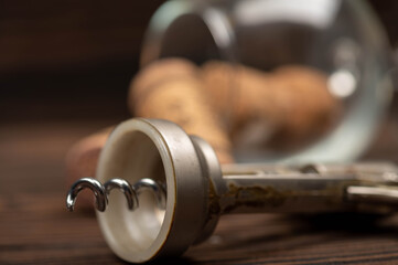 Corkscrew and corks from wine bottles on a wooden table.