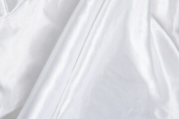 Obraz premium Colored white textile satin fabric folded in folds and waves with highlights and texture