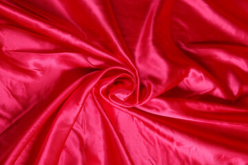 Obraz premium Colored red textile satin fabric folded in folds and waves with highlights and texture