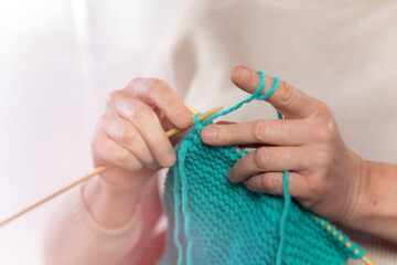 Frau strickt einen türkisen Schal aus Wolle