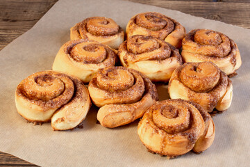 Freshly baked cinnamon buns with spices and cocoa filling on parchment paper. Sweet Homemade Pastry christmas baking. Close-up. Kanelbule - swedish dessert.