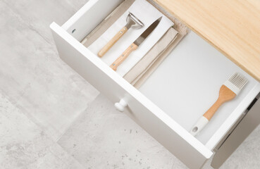 Fototapeta na wymiar Open kitchen drawer with towels, different cutlery and copy space