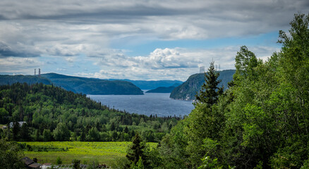 View point of fjord du Saguenay in Quebec Province on the East side with cloudy sky and windy weather. Green trees and grass on the foreground