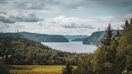 Old looking picture with wonderful view point of fjord du Saguenay in Quebec Province on the East side with cloudy sky and windy weather. Green trees and grass on the foreground