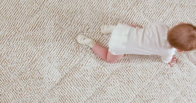 Baby crawling on the white blanket, top view