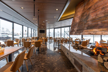 Interior of an empty mountain restaurant with large fireplace in the middle