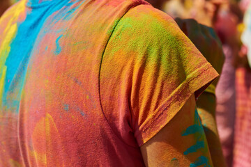 men's back in an orange T-shirt, which is all stained with multi-colored paint yellow and blue