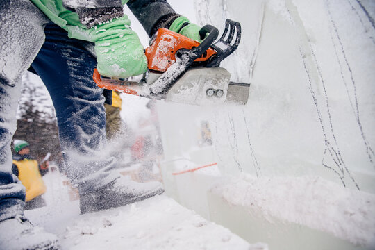 Ice sculpture carving man use chainsaw cut frozen winter