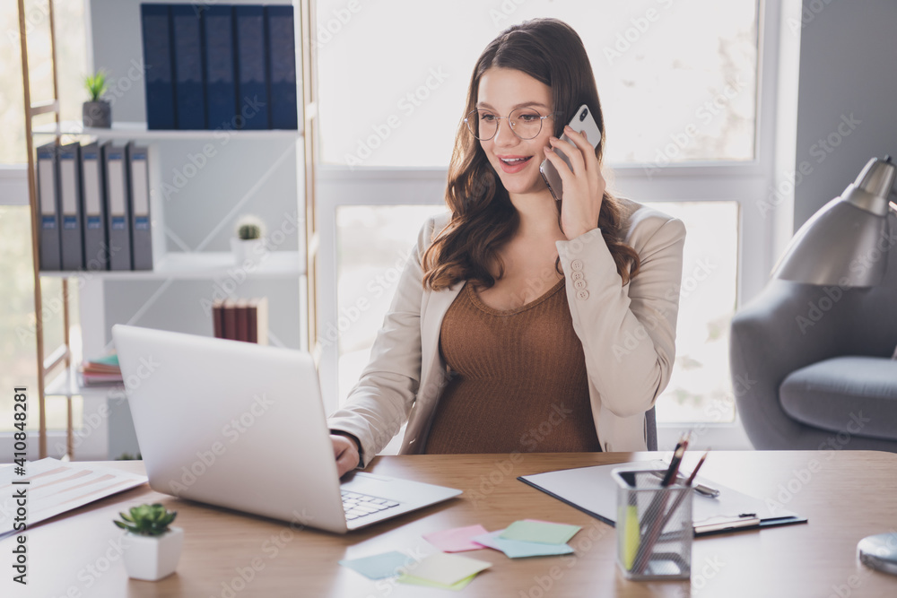 Canvas Prints Photo portrait of pregnant woman talking on phone tzping on laptop at desk in modern office