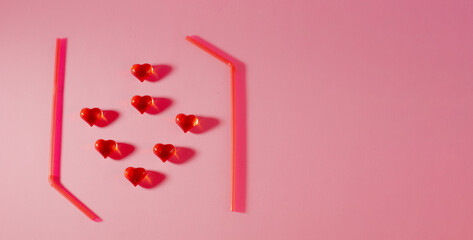 concept of a youth party. cocktail tubes and hearts on a pink background.