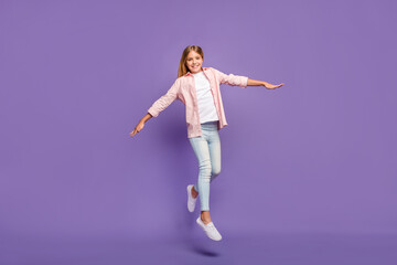 Full size photo of optimistic pretty girl jump show plain wear pink shirt jeans sneakers isolated...