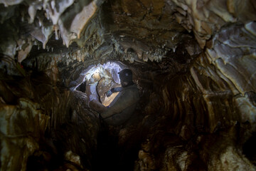 man in cave with lite with stalactites