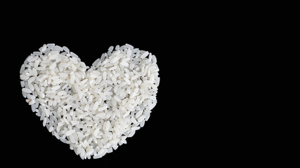 Heart shaped uncooked rice isolated on black background, closeup, top view, copy space. Can be used as a symbol of Thai, Japanese, Pan-Asian, Vietnamese cuisine