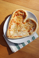 Heart shaped italian traditional Pizza on a plate on wooden table