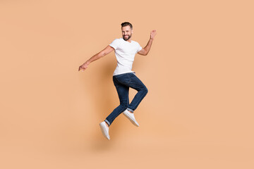 Fototapeta na wymiar Full length body size view of nice tall fit funky cheerful guy jumping having fun wearing cozy clothes isolated over beige color background